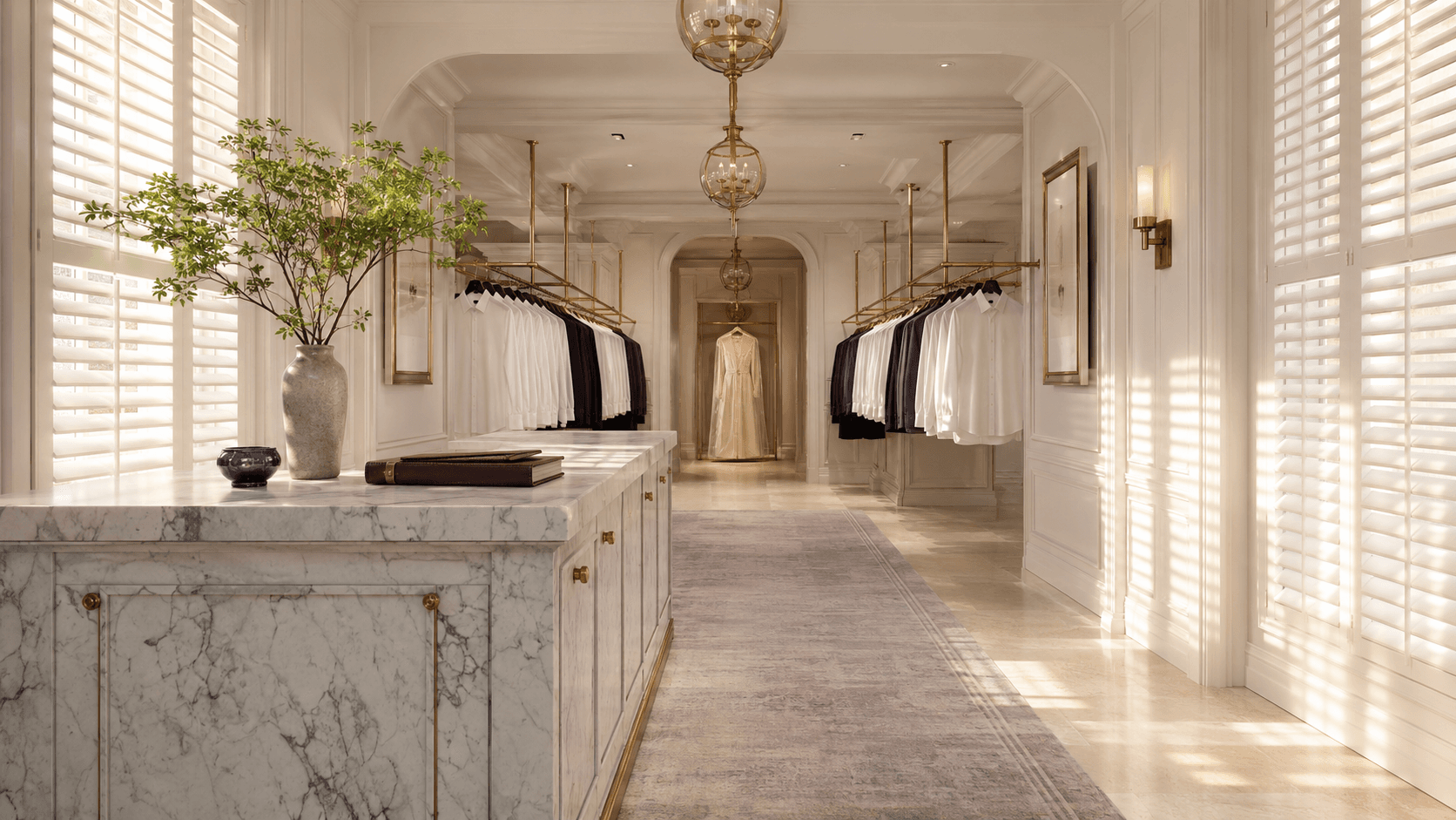 Sir Galloway showroom interior. Plantation shutters, marble counter, garments on brass rails.