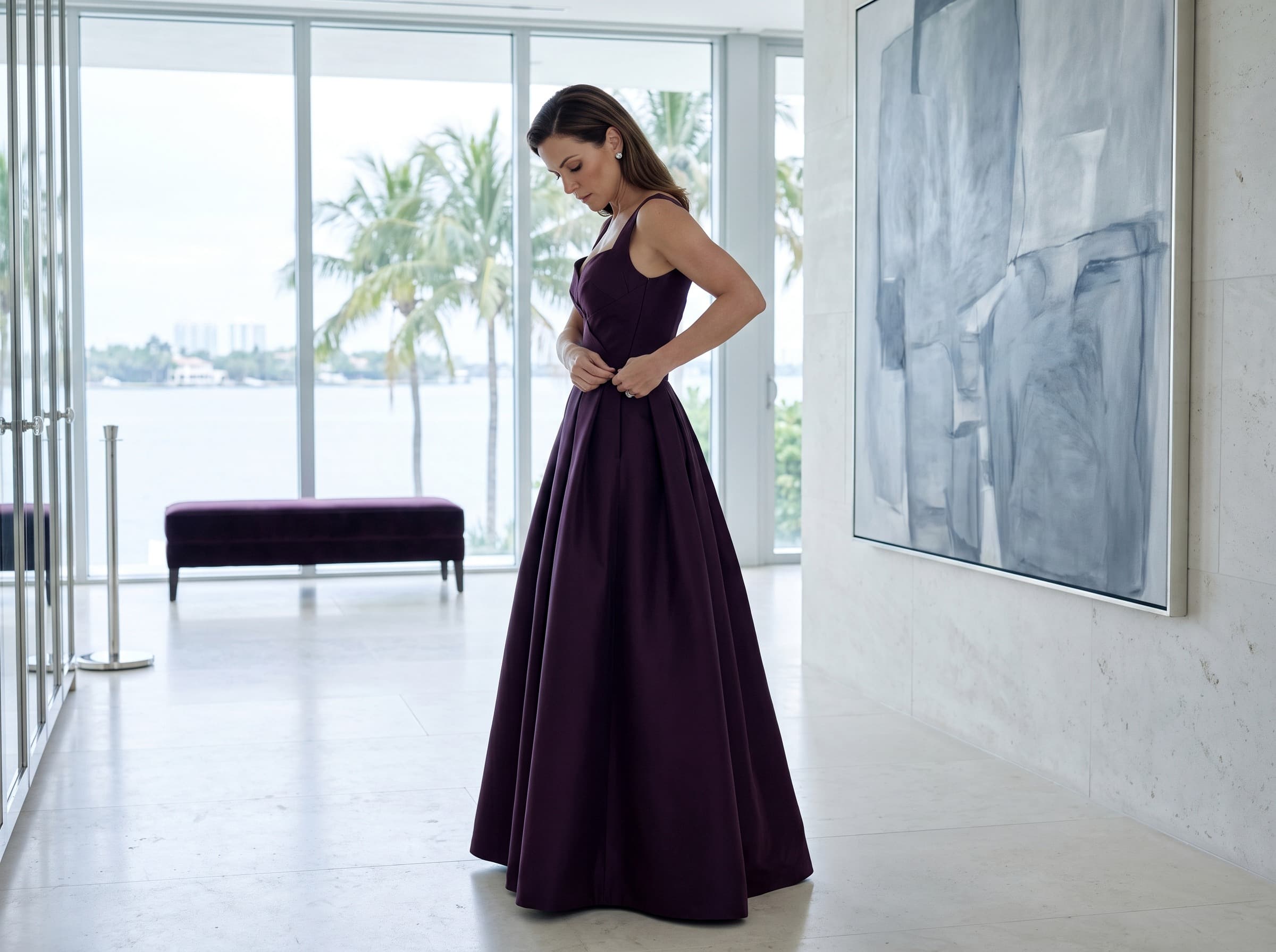 A woman in a floor-length deep plum evening gown with a pleated skirt.